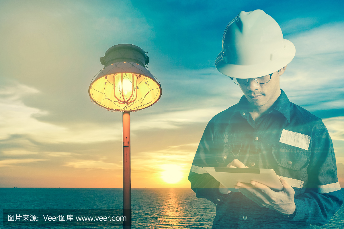 双重曝光的工程师或技术员在工作衬衫与平板电脑在灯和海洋背景的电力工业的概念。